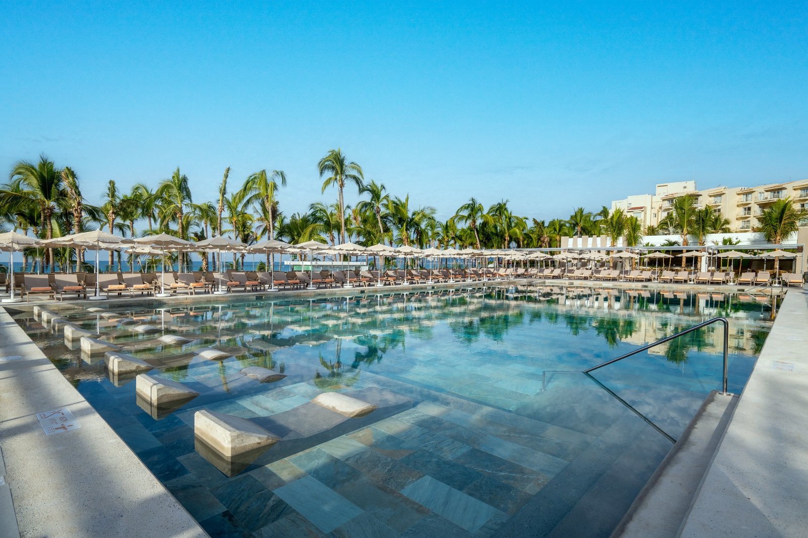 Ocean-facing pool with submerged loungers at RIU Palace Pacifico